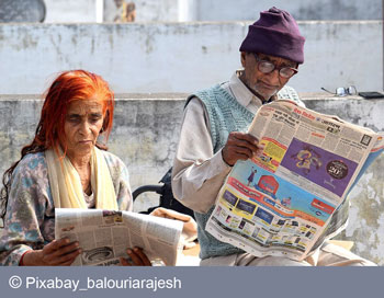 Ein Renterpaar liest Zeitungen auf einer Bank